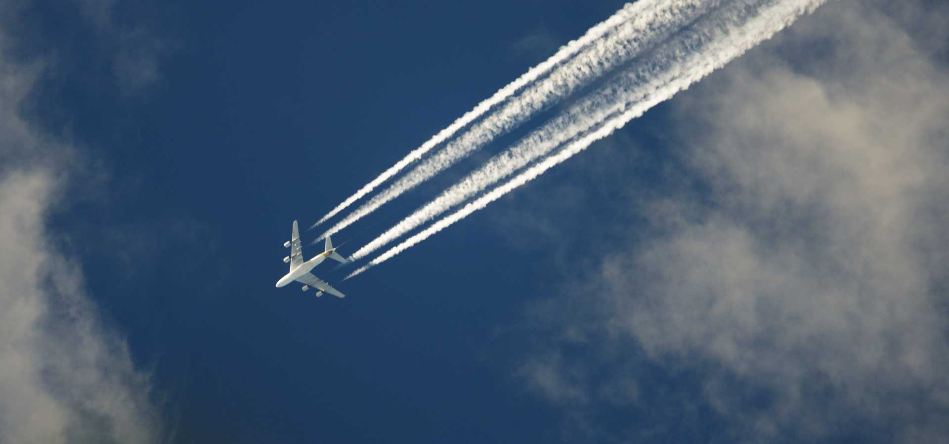 Commercial aircraft in sky with contrails