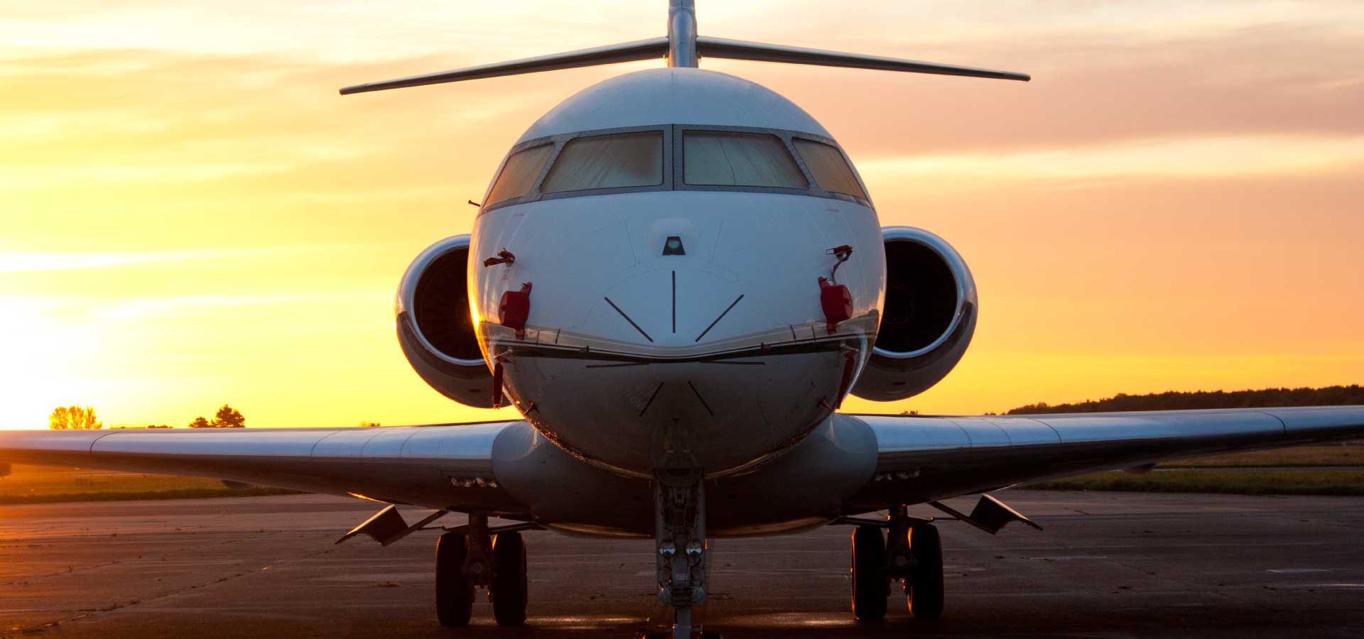 Private jet parked on ramp with evening sunset