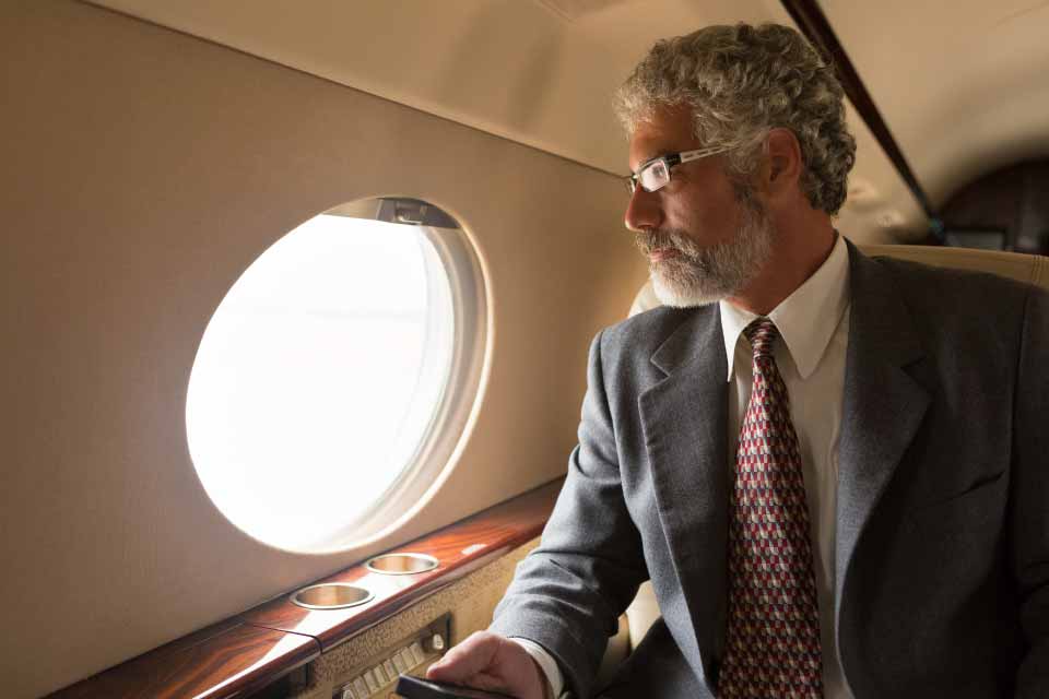 Businessman in aircraft looking out of window